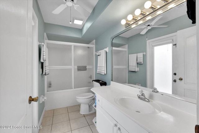 full bathroom featuring vanity, combined bath / shower with glass door, tile patterned flooring, ceiling fan, and toilet