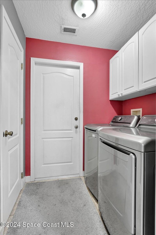 clothes washing area with cabinets, separate washer and dryer, a textured ceiling, and light carpet