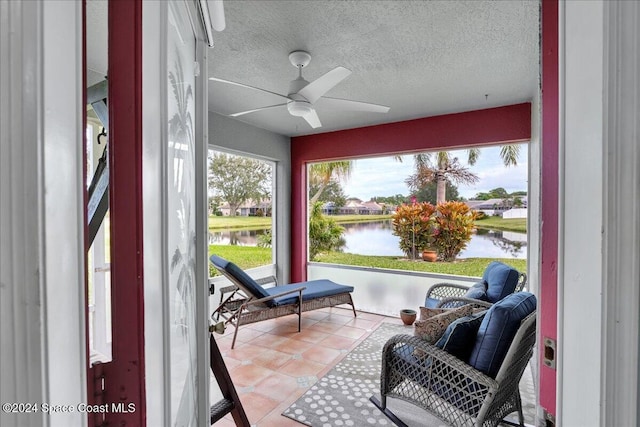 sunroom featuring ceiling fan and a water view