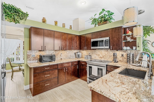 kitchen with dark brown cabinetry, light stone countertops, sink, and appliances with stainless steel finishes