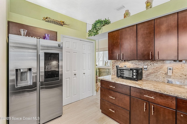 kitchen with decorative backsplash, stainless steel fridge with ice dispenser, light stone counters, and dark brown cabinets