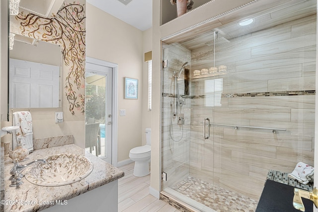 bathroom with walk in shower, vanity, and toilet