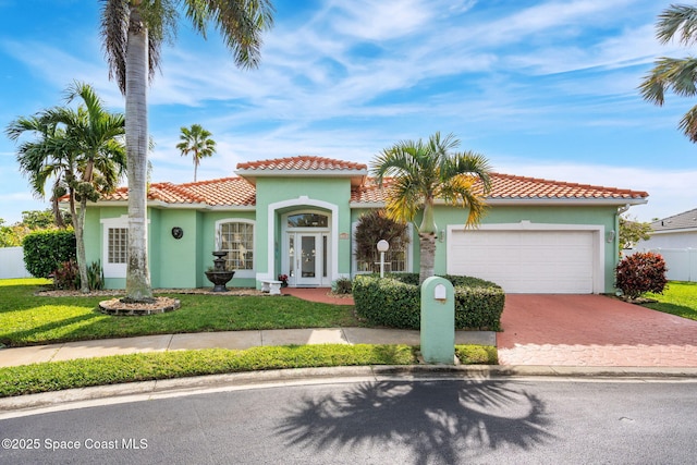 mediterranean / spanish-style house with a garage and a front lawn