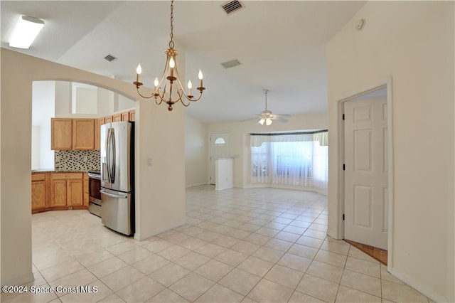 kitchen with decorative backsplash, stainless steel fridge, ceiling fan with notable chandelier, vaulted ceiling, and light tile patterned floors