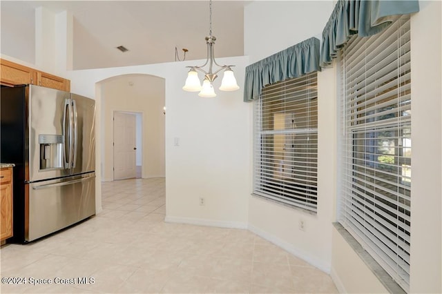 kitchen with light tile patterned flooring, pendant lighting, stainless steel refrigerator with ice dispenser, and a notable chandelier