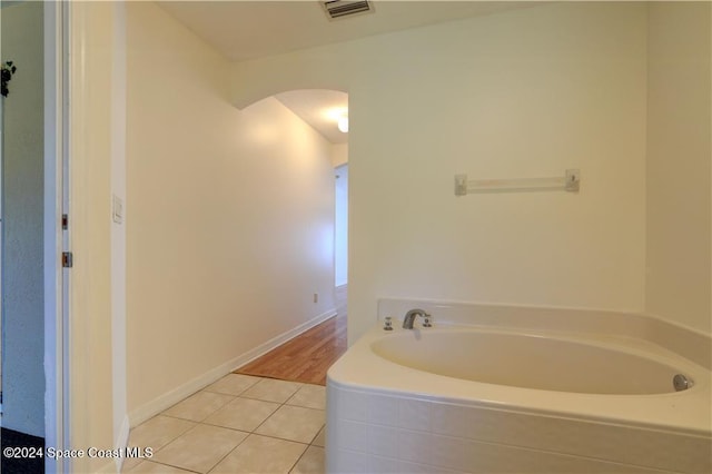 bathroom with tile patterned floors and tiled tub