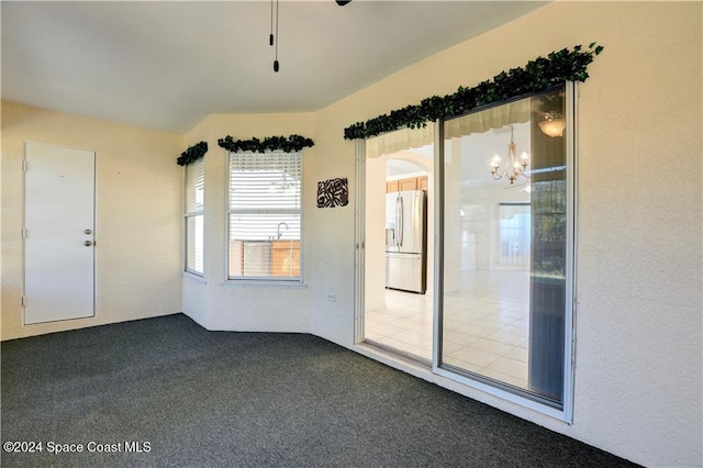 carpeted spare room featuring an inviting chandelier