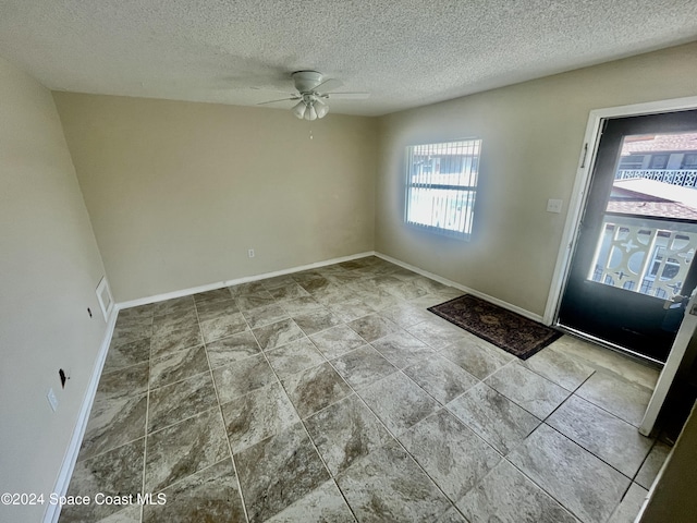 foyer with a textured ceiling and ceiling fan