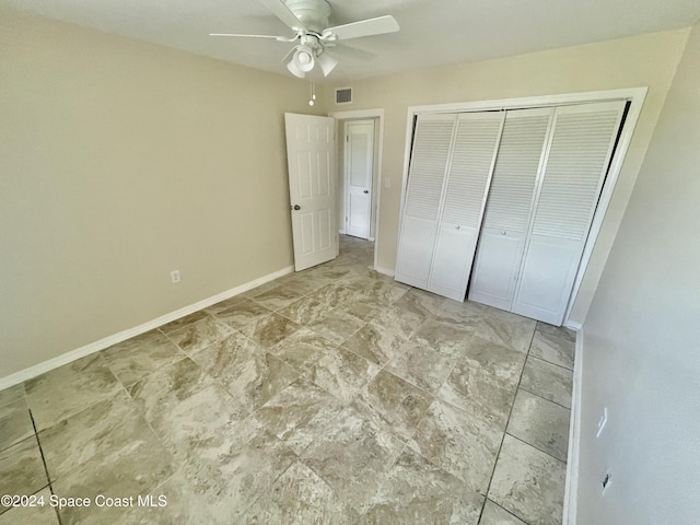 unfurnished bedroom with ceiling fan and a closet