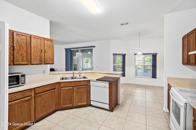 kitchen featuring white appliances, sink, light tile patterned floors, decorative light fixtures, and kitchen peninsula