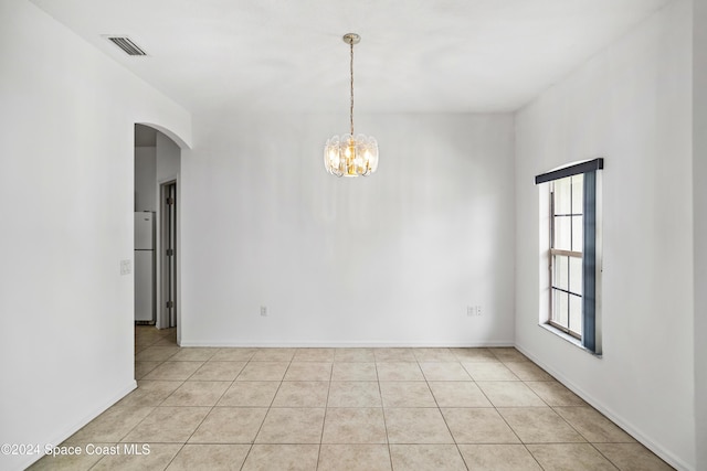 empty room with light tile patterned floors and a chandelier