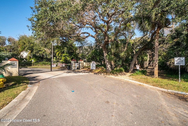 view of street featuring a gate, curbs, and a gated entry