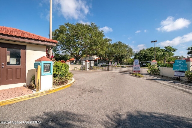 view of street with curbs, a gated entry, and a gate