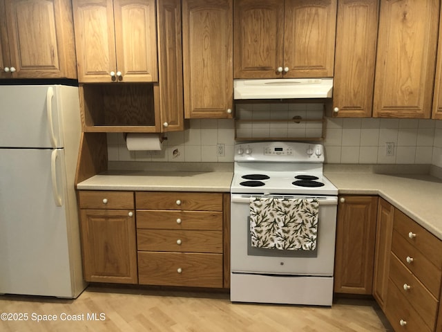 kitchen featuring white appliances, light wood finished floors, brown cabinets, and under cabinet range hood