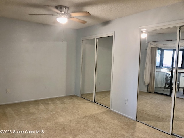 unfurnished bedroom featuring two closets, baseboards, carpet, and a textured ceiling