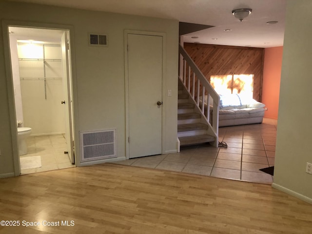 interior space with visible vents, wood finished floors, wood walls, and stairway