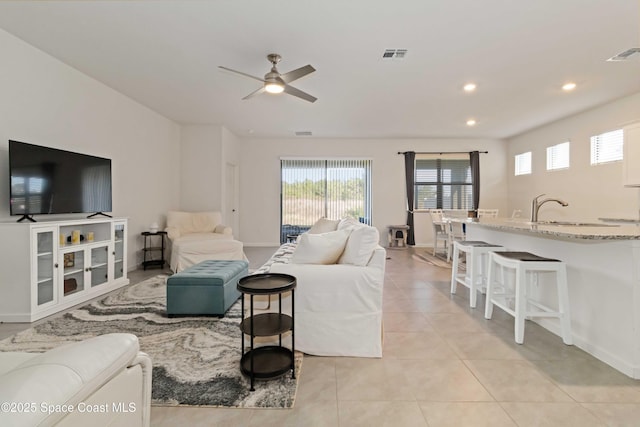 living room featuring ceiling fan, sink, and light tile patterned floors