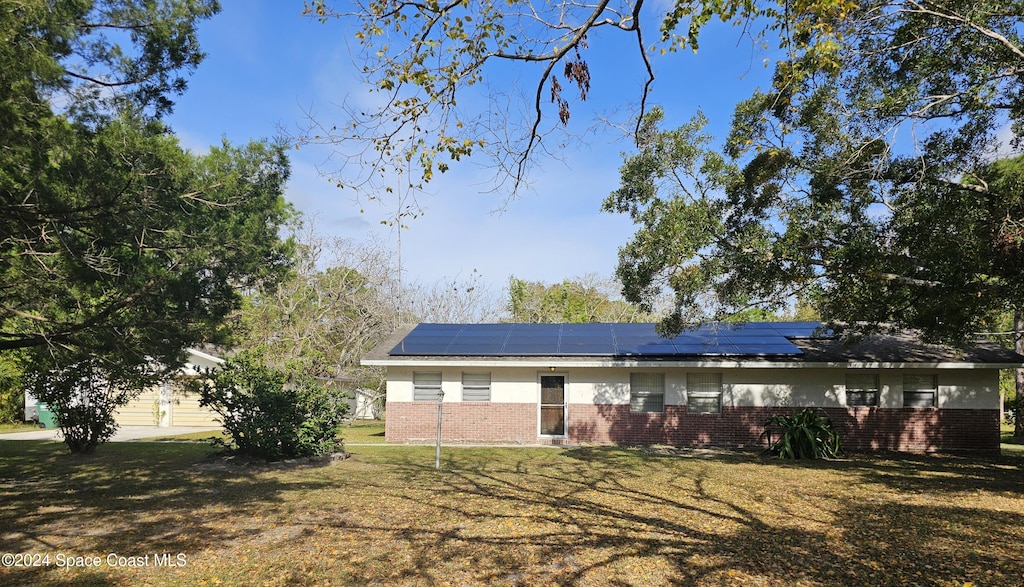 view of front of property with a front yard and solar panels