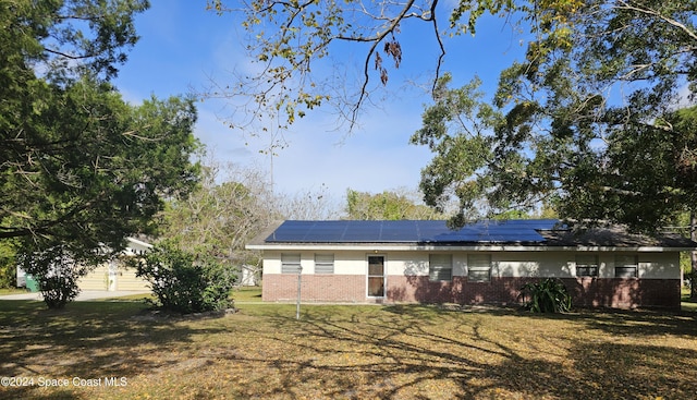 view of front of property with a front yard and solar panels