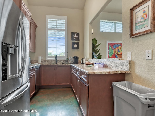 kitchen featuring kitchen peninsula, light stone countertops, sink, dishwasher, and stainless steel fridge with ice dispenser