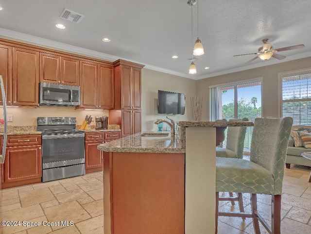 kitchen with appliances with stainless steel finishes, hanging light fixtures, ornamental molding, and sink