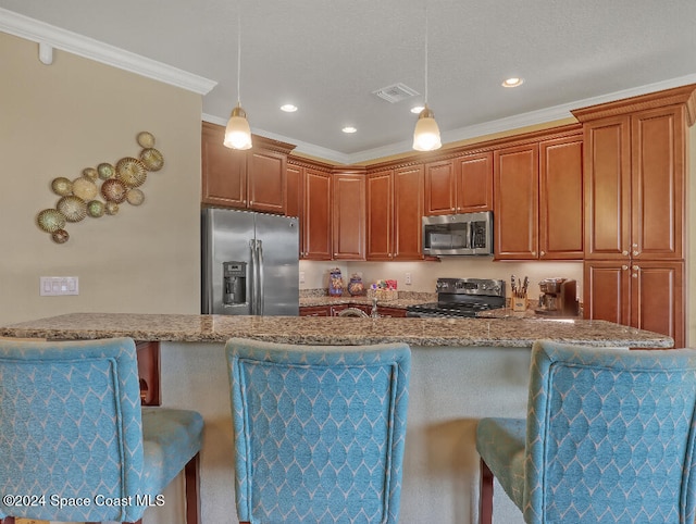 kitchen with appliances with stainless steel finishes, light stone counters, ornamental molding, decorative light fixtures, and a breakfast bar area