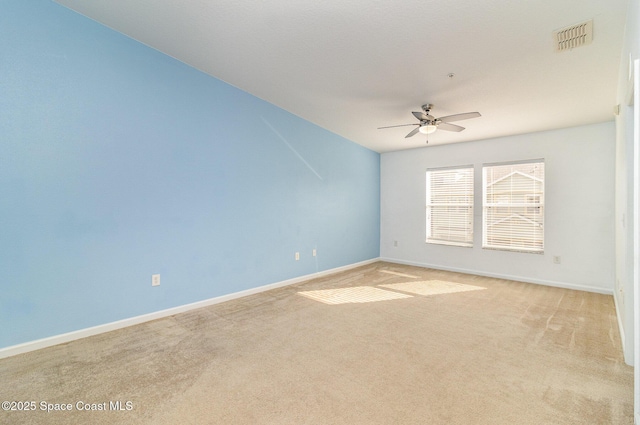 empty room featuring a ceiling fan, visible vents, light carpet, and baseboards