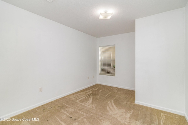 empty room with a textured ceiling, baseboards, and carpet flooring