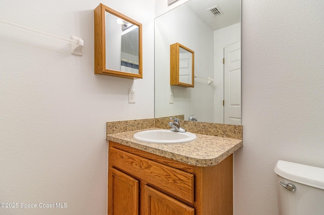 bathroom with visible vents, vanity, and toilet