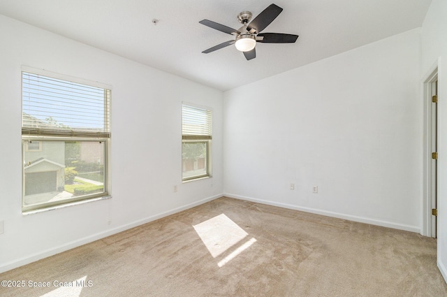 carpeted spare room featuring ceiling fan and baseboards