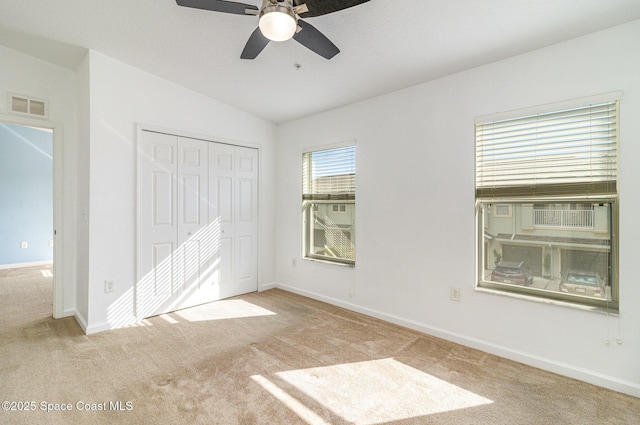 unfurnished bedroom with carpet, a closet, visible vents, vaulted ceiling, and baseboards