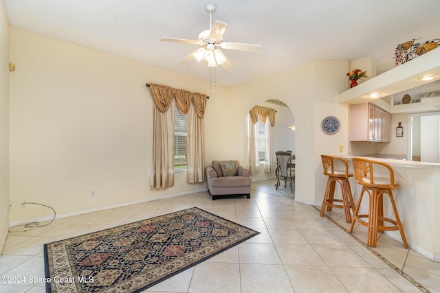 living room with light tile patterned floors, a textured ceiling, and ceiling fan