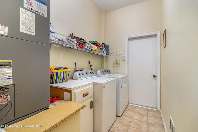 washroom with heating unit, light tile patterned floors, a textured ceiling, and independent washer and dryer