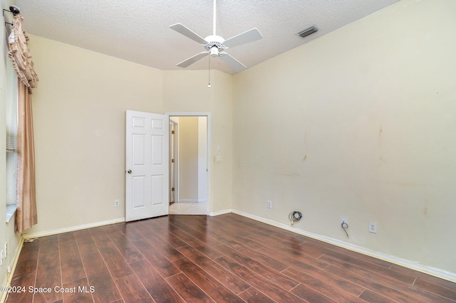 empty room with a towering ceiling, a textured ceiling, dark hardwood / wood-style flooring, and ceiling fan