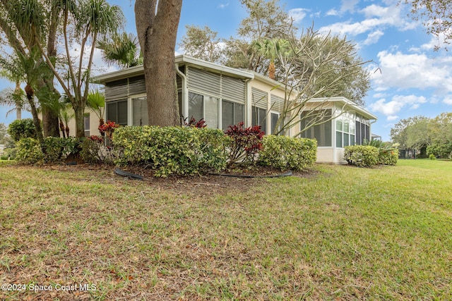 view of side of property featuring a sunroom and a yard