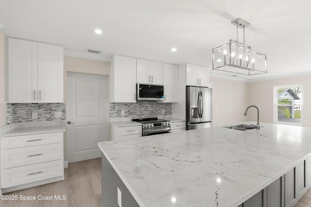 kitchen featuring pendant lighting, sink, stainless steel appliances, and a kitchen island with sink