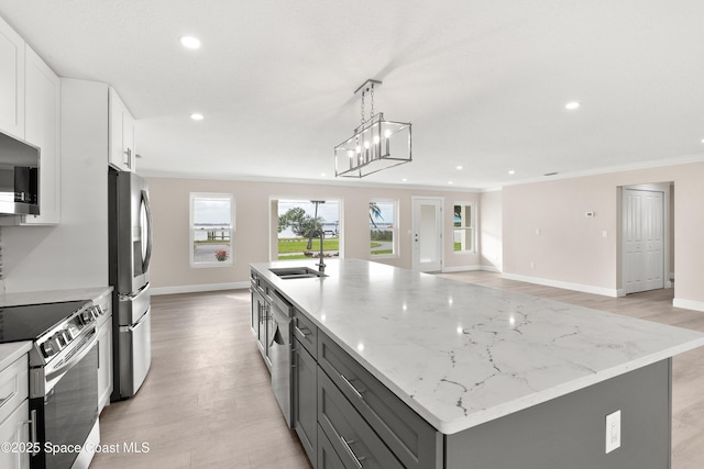 kitchen featuring white cabinetry, sink, hanging light fixtures, stainless steel appliances, and a center island with sink