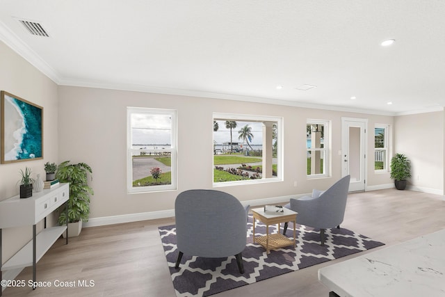 living area with crown molding and light hardwood / wood-style flooring