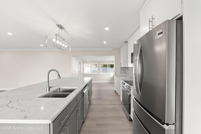 kitchen with white cabinets, sink, an island with sink, decorative light fixtures, and stainless steel appliances