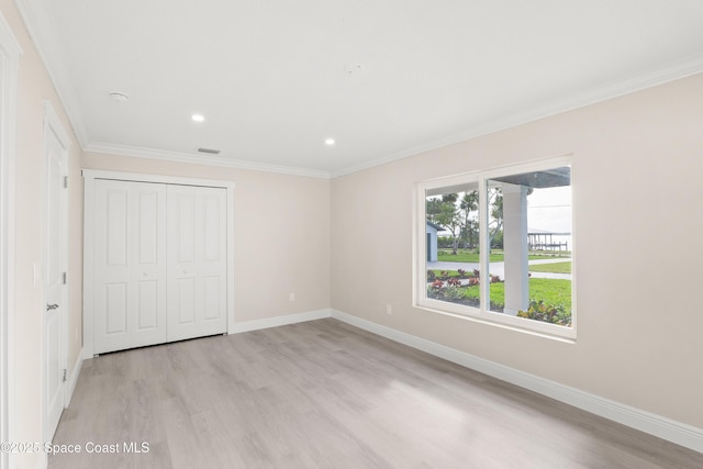 unfurnished bedroom featuring a closet, light hardwood / wood-style floors, multiple windows, and ornamental molding