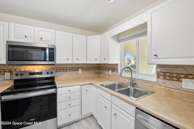 kitchen with white cabinets, backsplash, sink, and appliances with stainless steel finishes