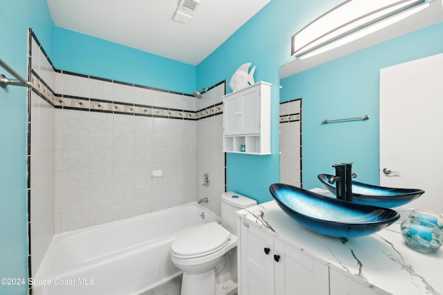 full bathroom featuring vanity, tiled shower / bath combo, and toilet