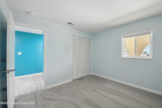 unfurnished bedroom with light colored carpet and a closet