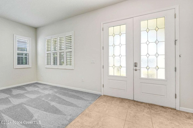 entrance foyer featuring french doors and light colored carpet