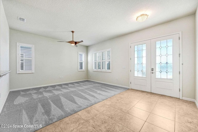 tiled foyer with ceiling fan, french doors, and a textured ceiling