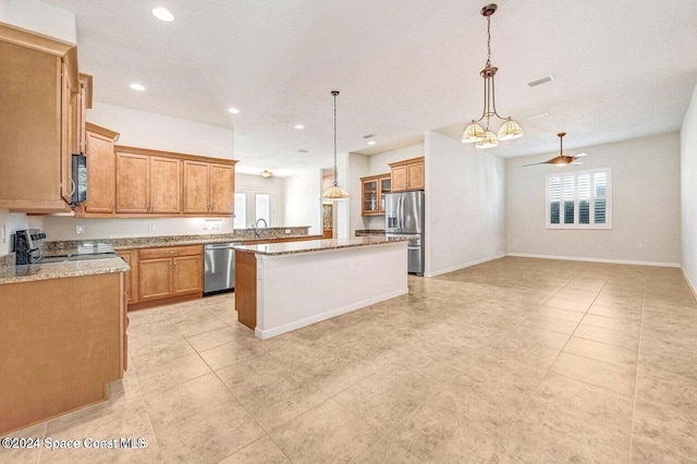 kitchen featuring a center island, sink, light stone countertops, appliances with stainless steel finishes, and decorative light fixtures