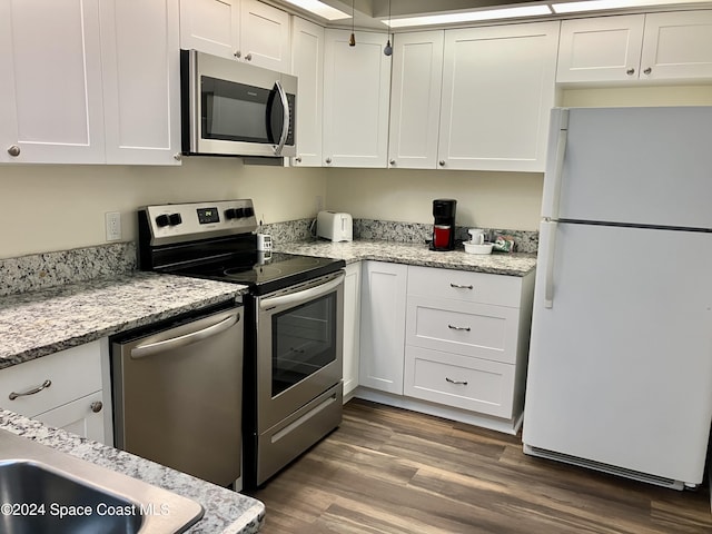 kitchen with light stone countertops, appliances with stainless steel finishes, dark wood-style floors, and white cabinetry