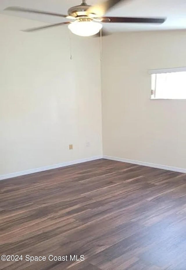 unfurnished room featuring baseboards, dark wood-style floors, and a ceiling fan