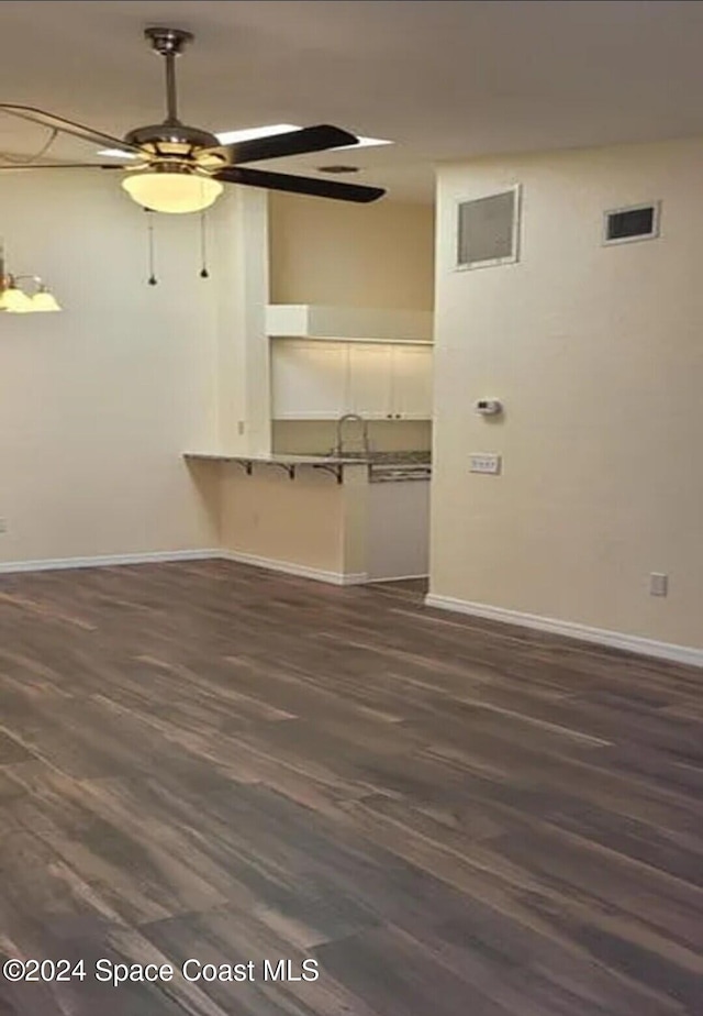 empty room featuring visible vents, baseboards, dark wood-style floors, and a ceiling fan