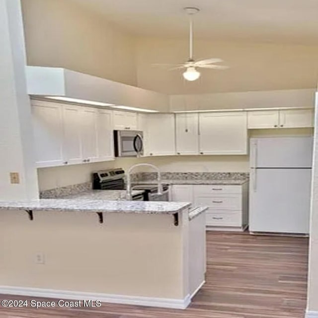 kitchen with a breakfast bar area, appliances with stainless steel finishes, white cabinetry, and a peninsula